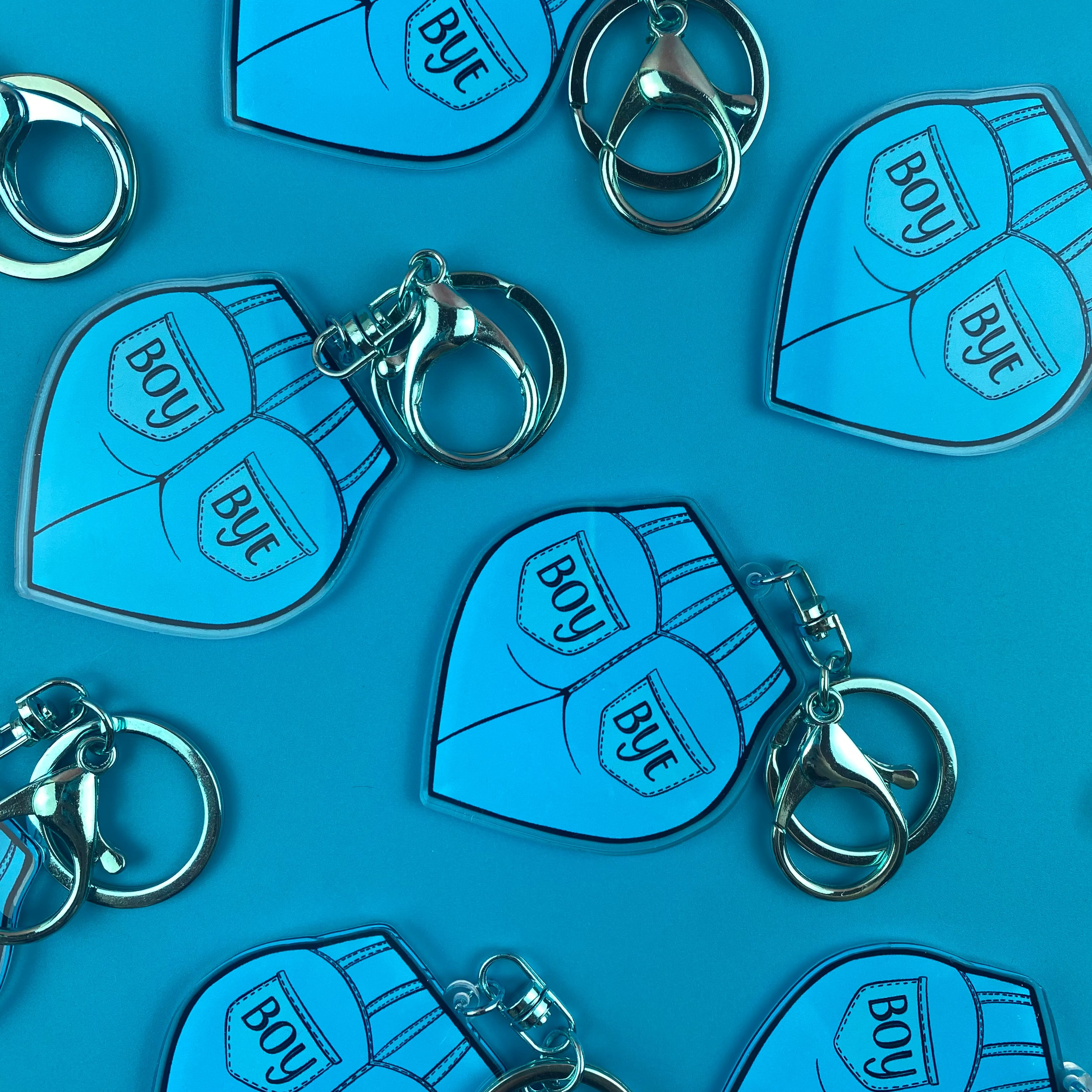 Blue keychains with 'BOY' and 'BYE' text on a blue background