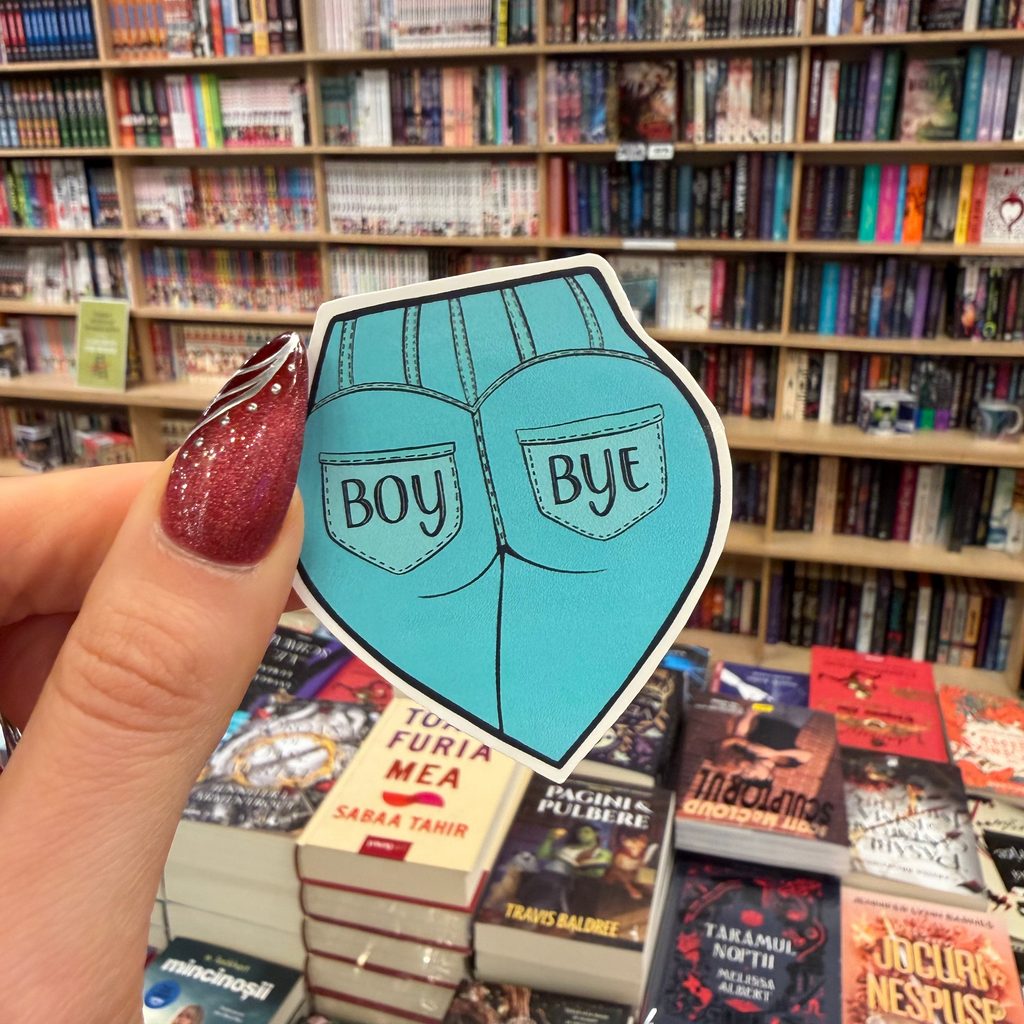 Hand holding a blue 'Boy Bye' sticker in front of a bookshelf filled with books.
