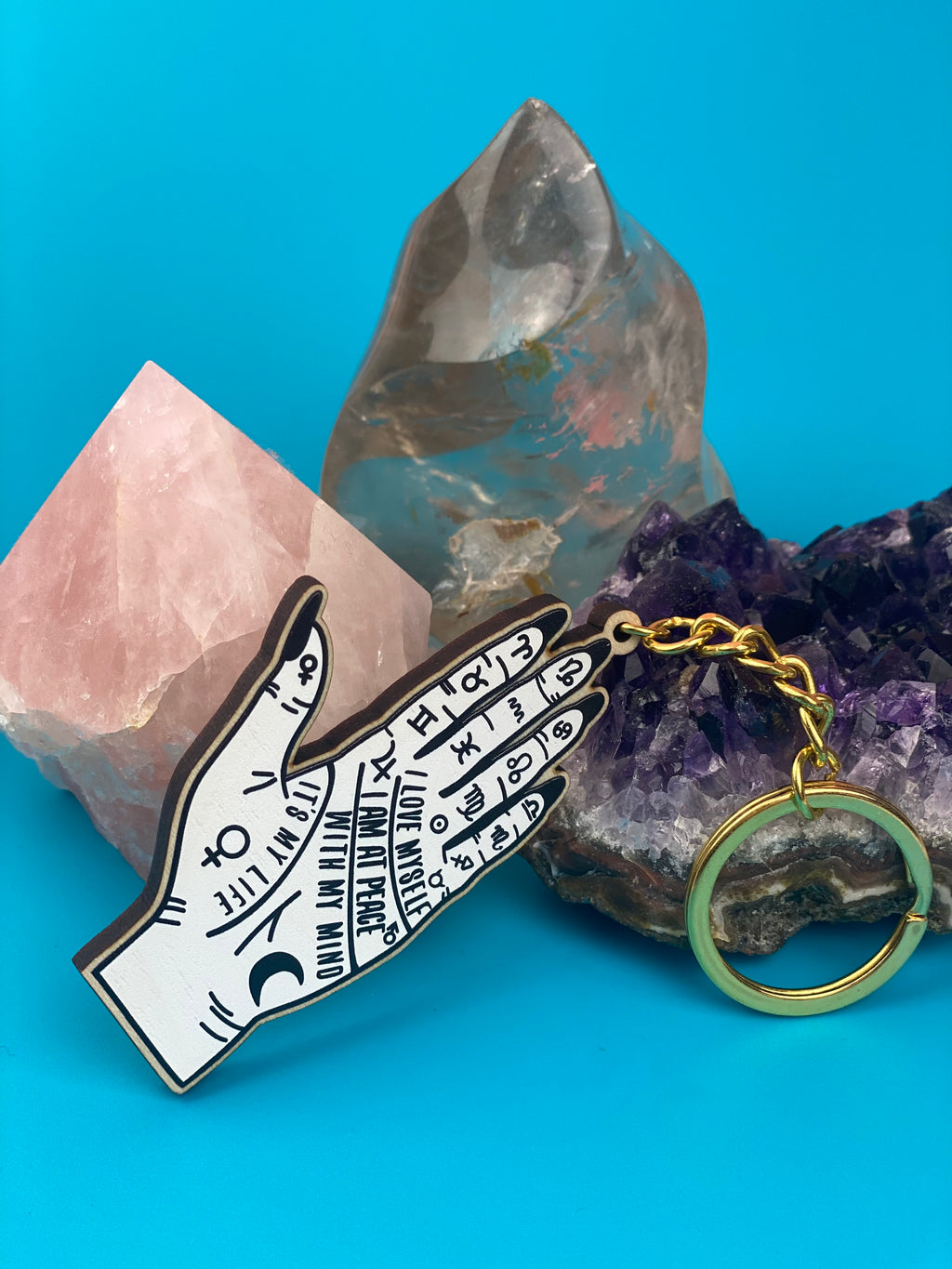 Hand-shaped keychain with symbols on a blue background with crystals