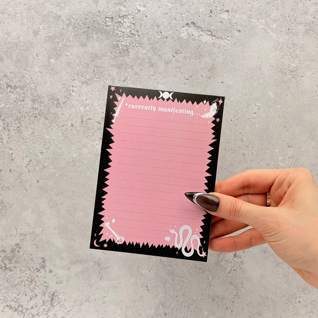 Hand holding a pink card with black border on a gray textured background