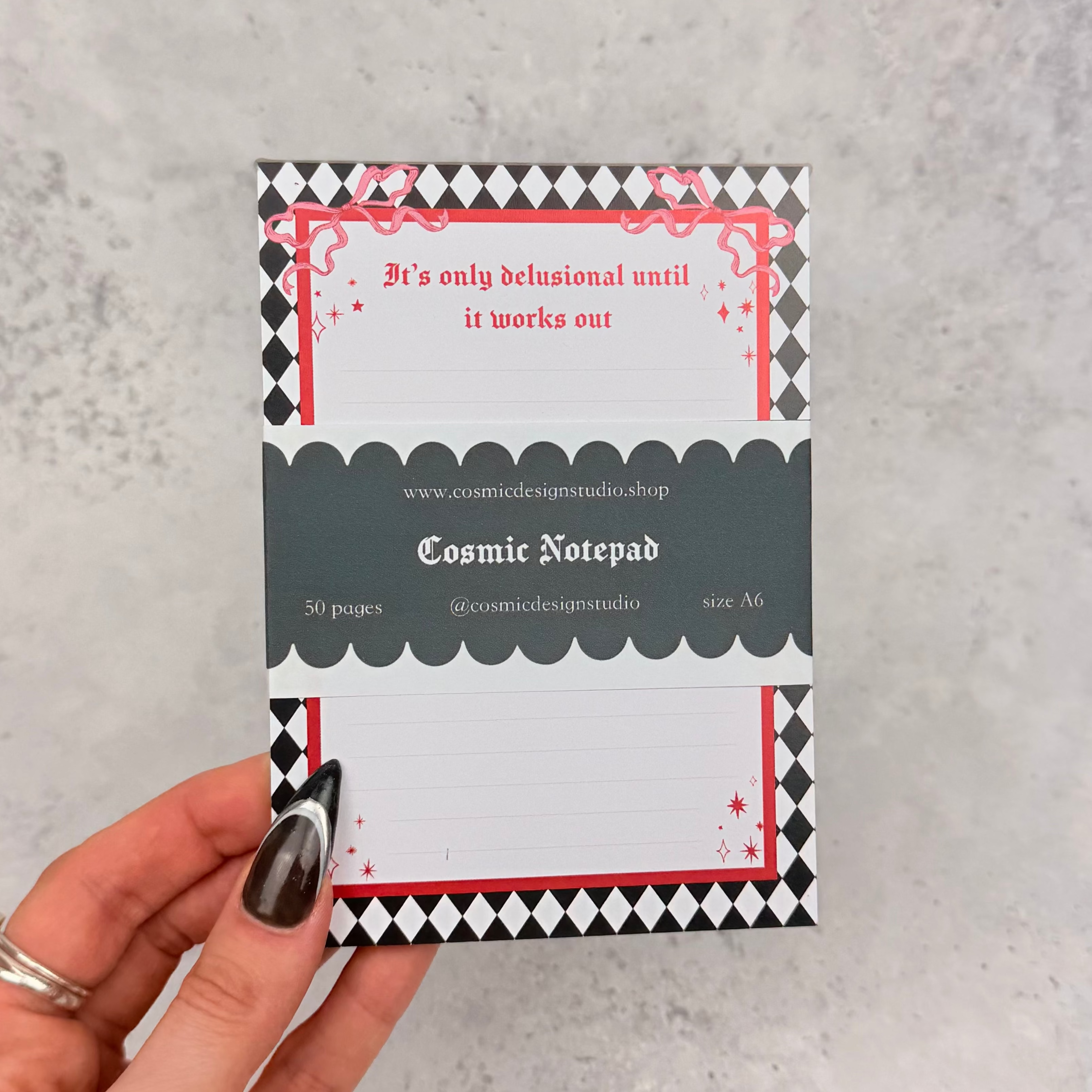Notepad with decorative border and pen on a gray surface