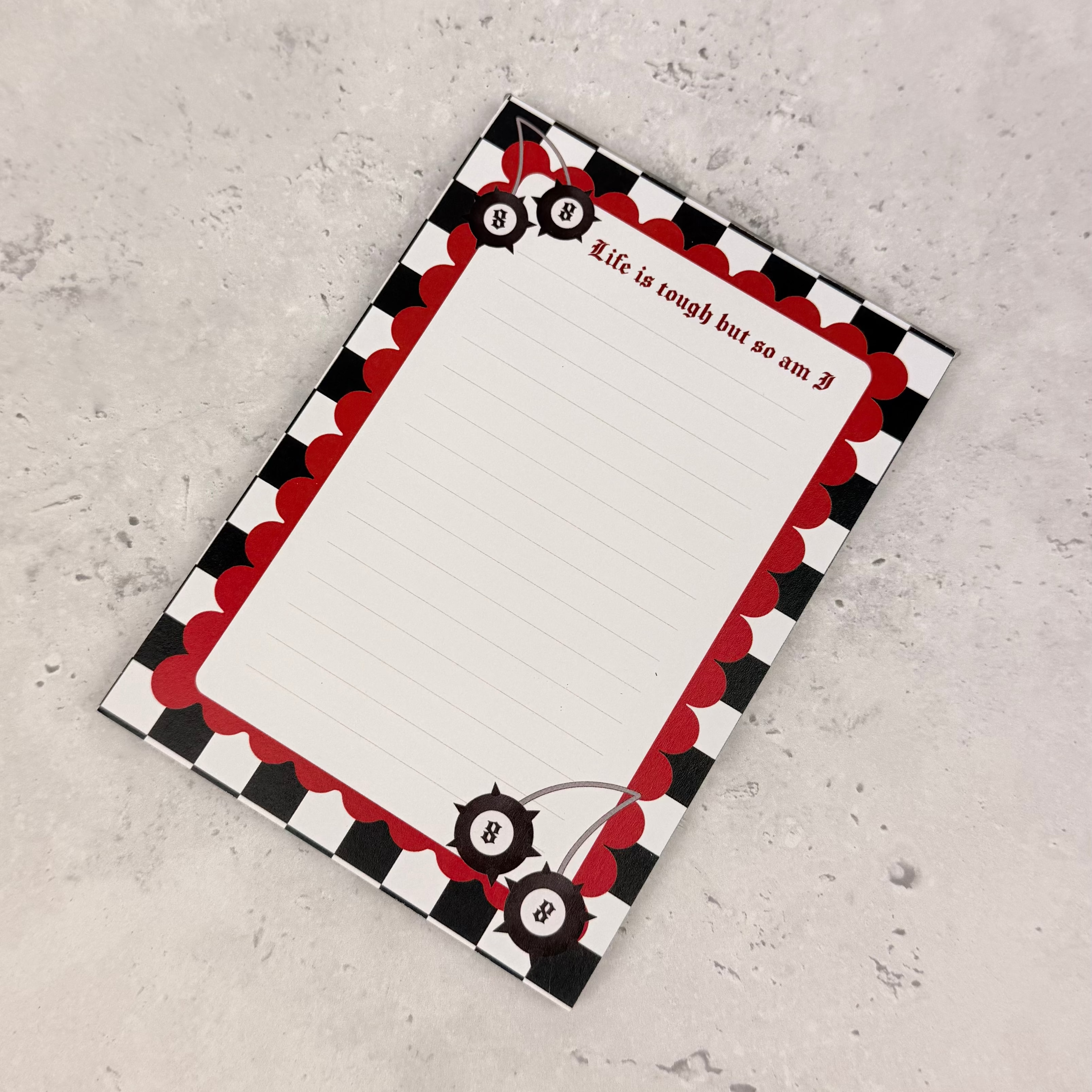 Notepad with a red and black checkered border on a gray surface